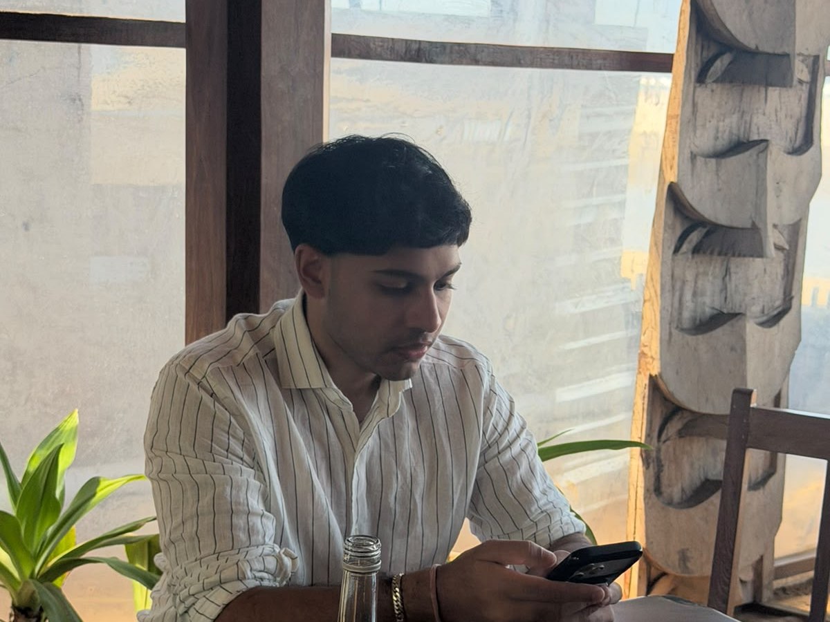 Ahaan Singhania at a table by a window in Goa, reading his phone